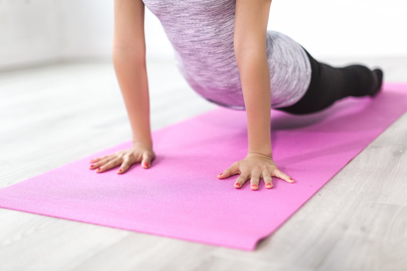 Frau dehnt sich auf einer Yogamatte